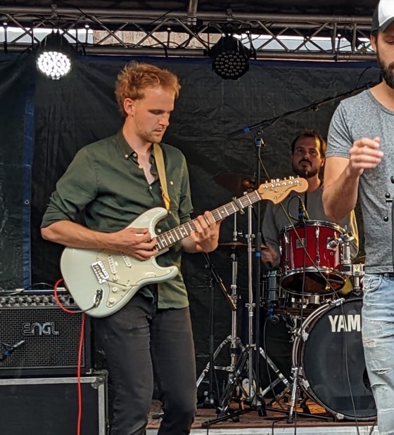 Maarten playing guitar with his band on an outdoor stage